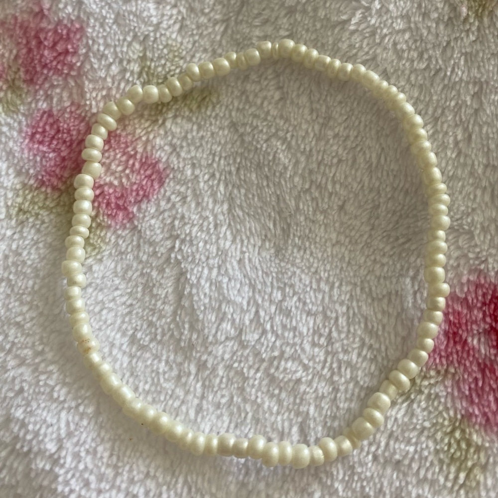 A tan color seed bead style ankle bracelet .
